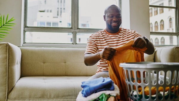 man zit op zetel en is kleding aan het plooien